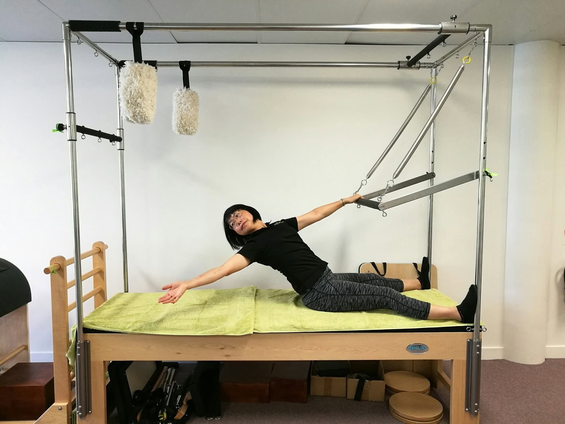 A client performing a side stretch on the Cadillac